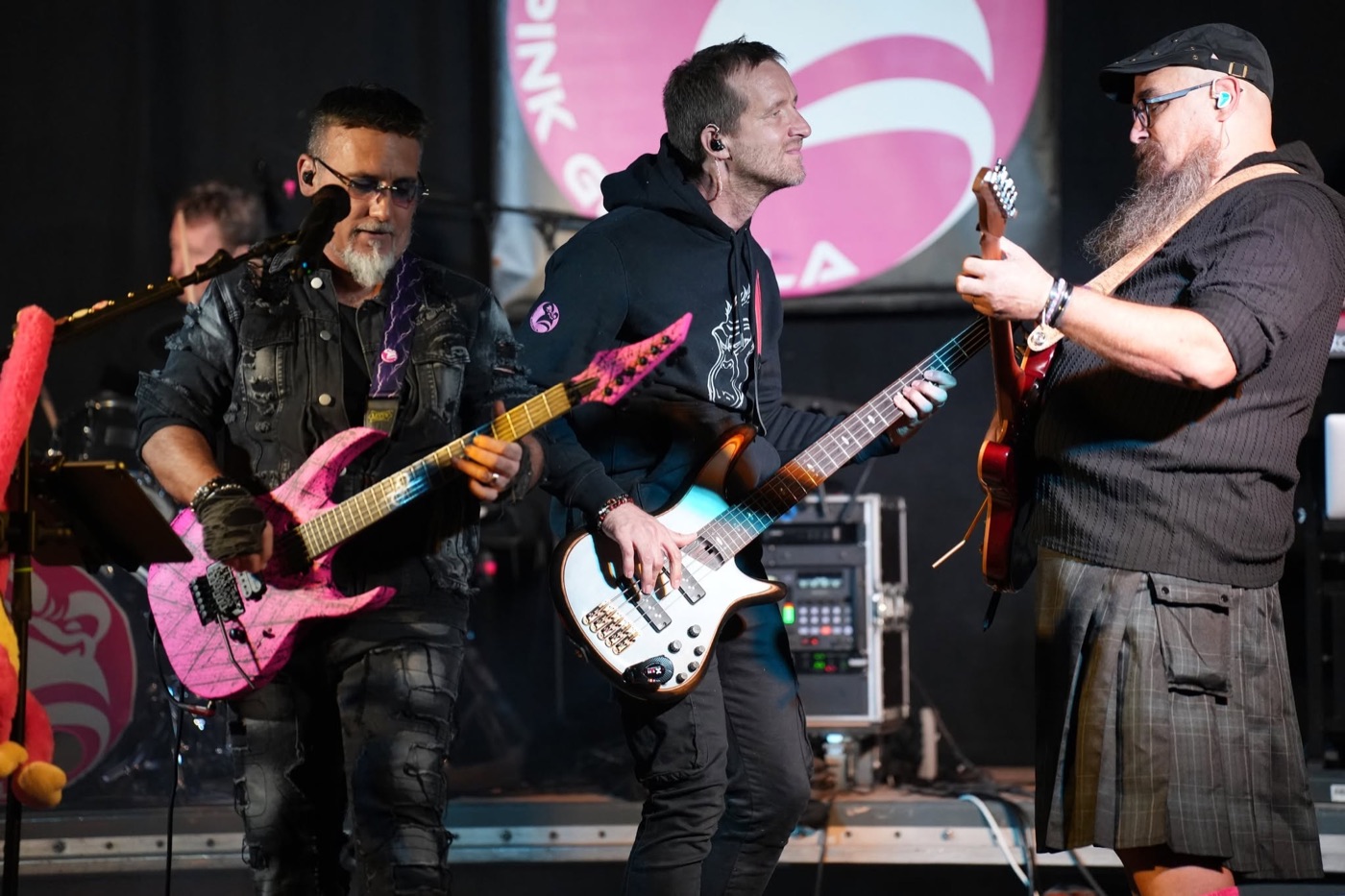 Deux guitaristes et le bassiste de PINK GORILLA réunis au premier plan sur scène.