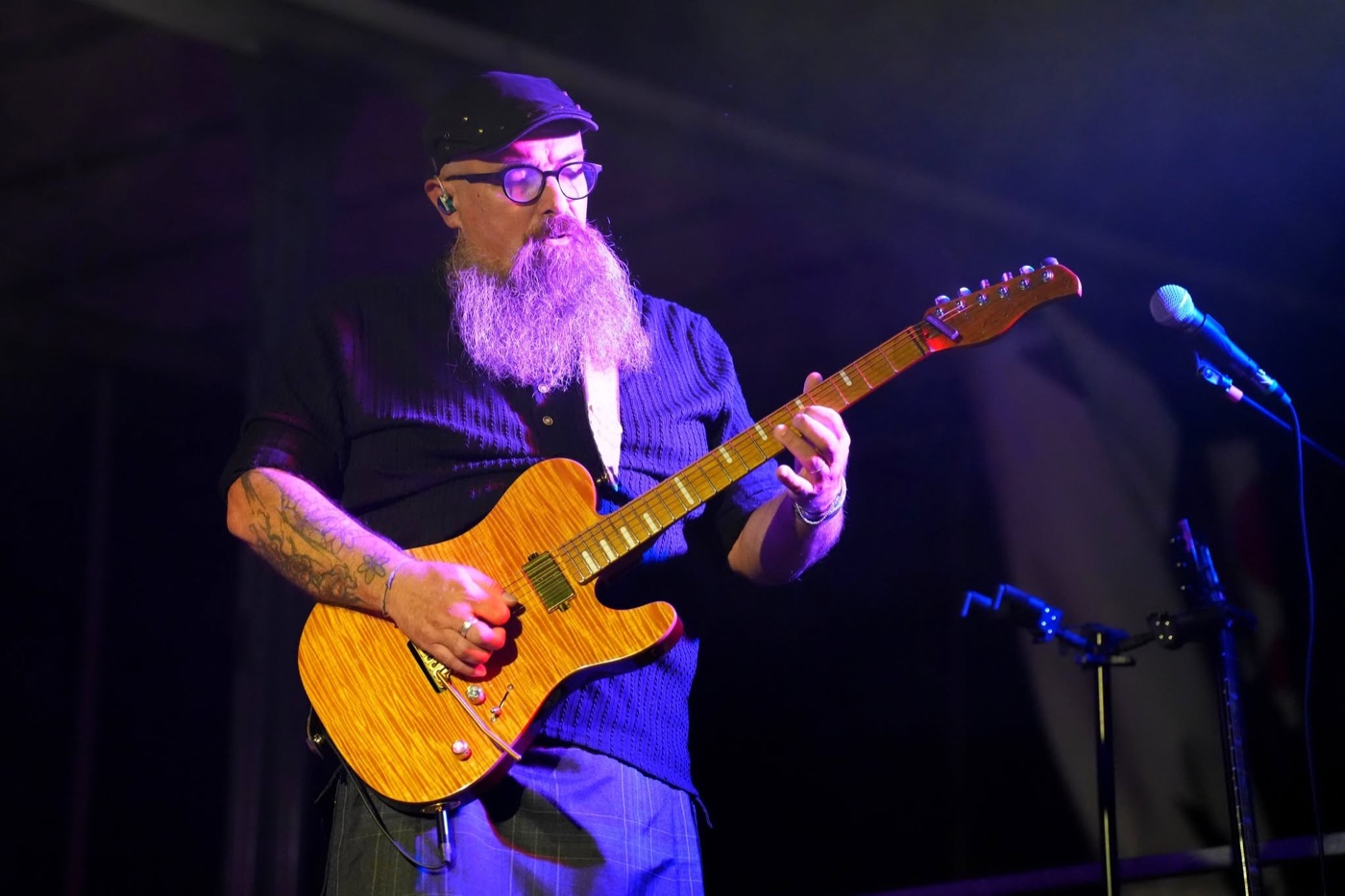 Guitariste de PINK GORILLA jouant une guitare couleur bois sous un éclairage violet.