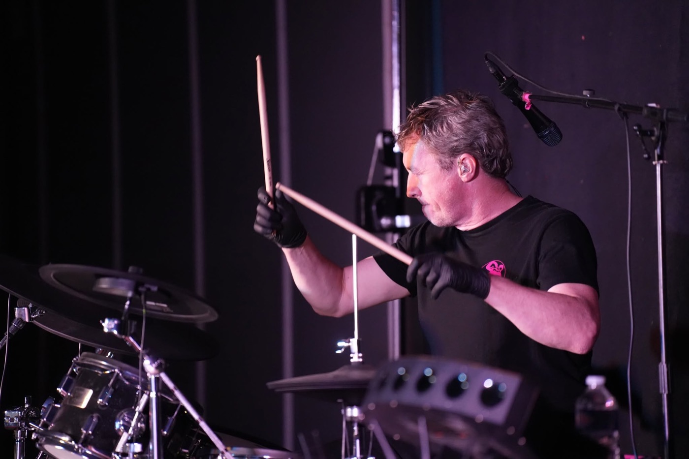 Batteur de PINK GORILLA, baguettes levées, photographié au cours du concert.
