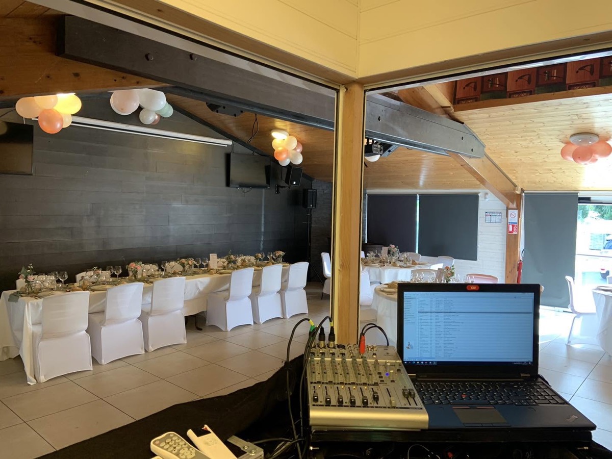 Régie avec ordinateur et table de mixage devant une salle de réception décorée à Chambon-sur-Lac.