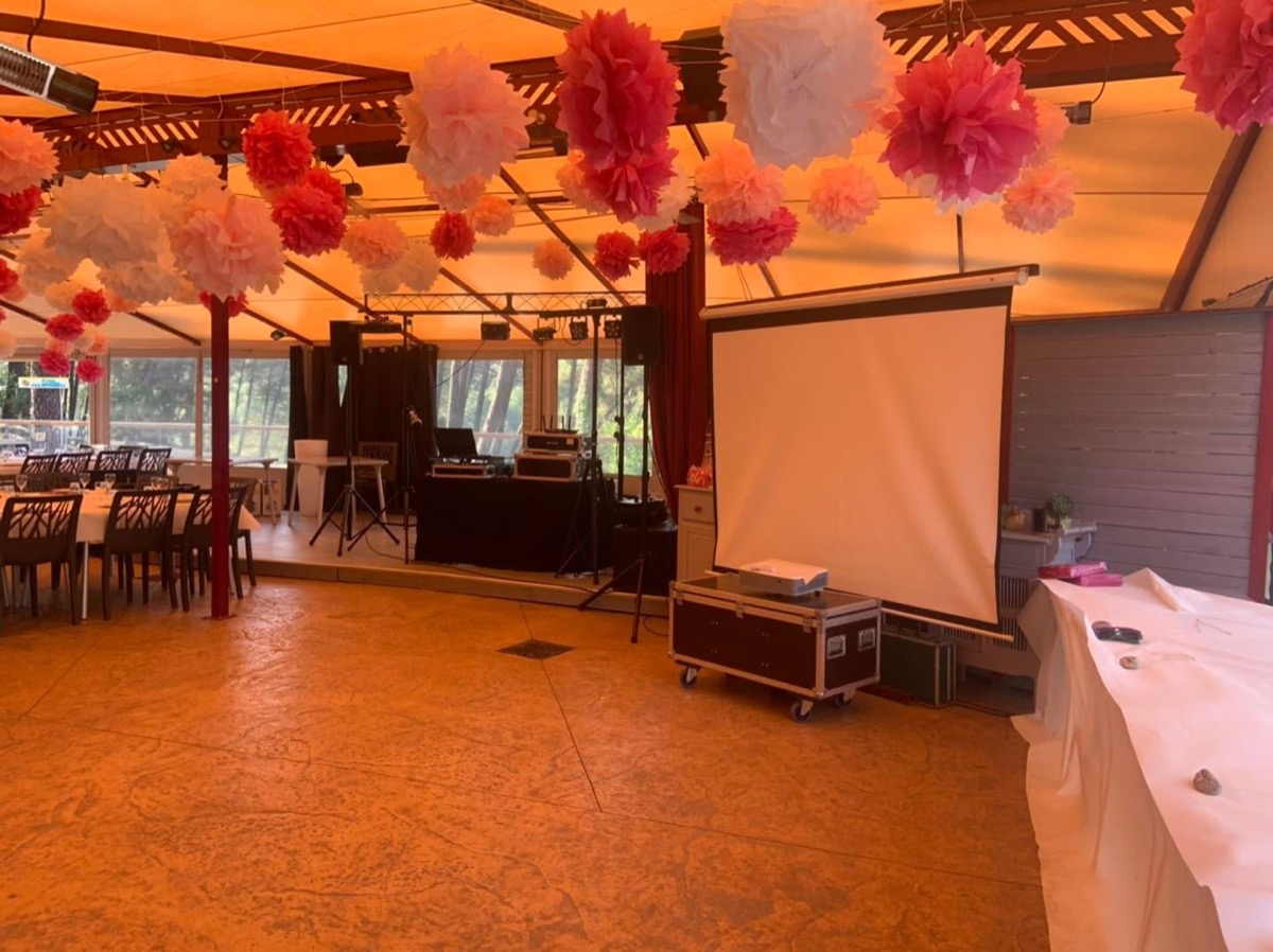 Installation DJ et vidéoprojection dans une salle de mariage décorée de suspensions roses et blanches en Ardèche.