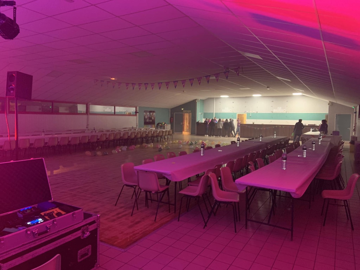Salle de soirée karaoké préparée à Rochefort-Montagne, avec tables, éclairage violet et matériel d’animation.